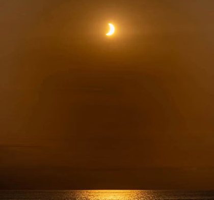 The partly eclipsed sun low over the Atlantic