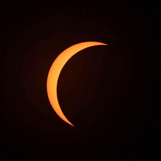 The sun reduced to a narrow orange crescent