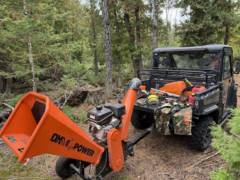 A DK2 Power tow-behind chipper parked in the bush beside a side-by-side