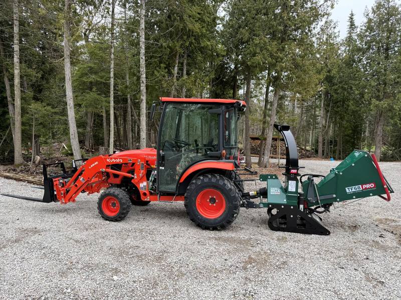 A Kubota tractor with a Woodland Mills TF68 PRO chipper on the three-point hitch